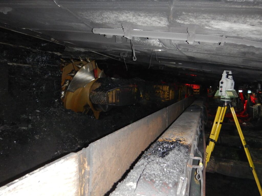 Underground mining tunnel with machinery and conveyor system.