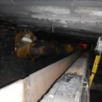 Underground mining tunnel with machinery and conveyor system.