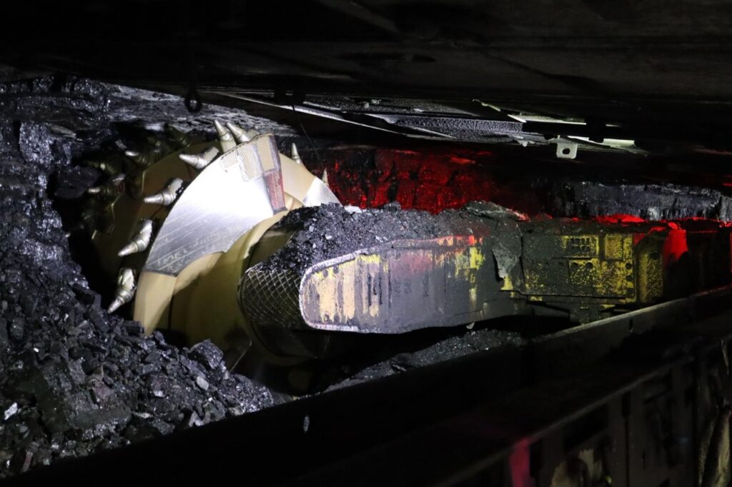 Coal mining machinery working underground to extract coal.