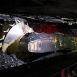 Coal mining machinery working underground to extract coal.