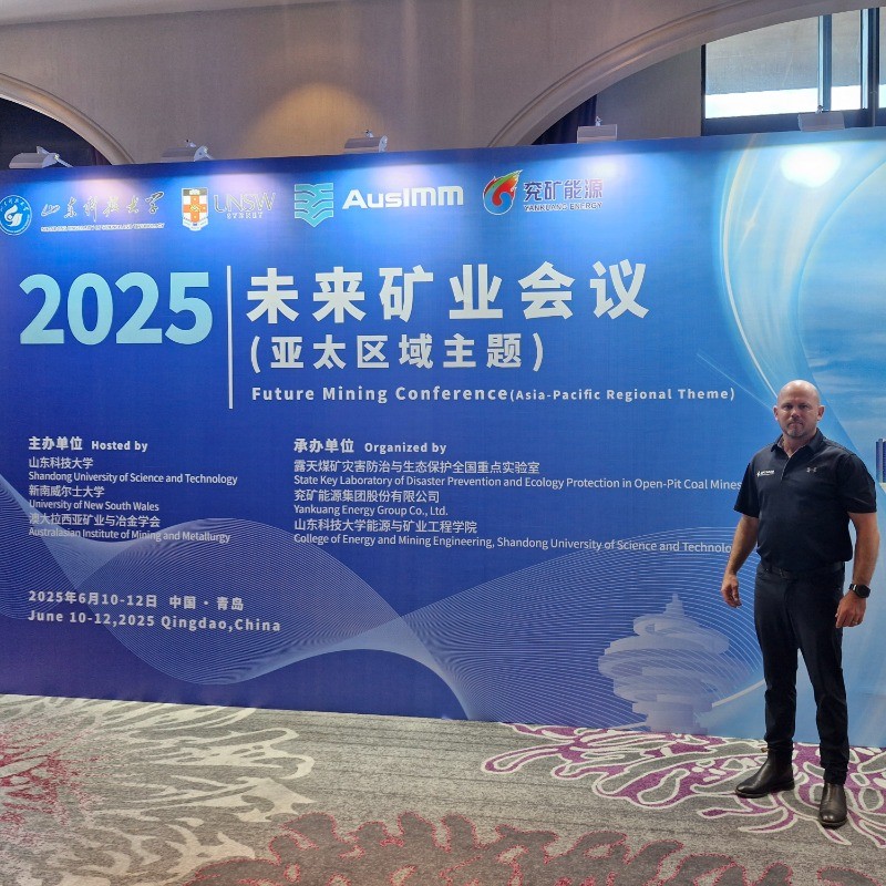Man standing next to a 2025 Future Industry Conference banner in a convention center.